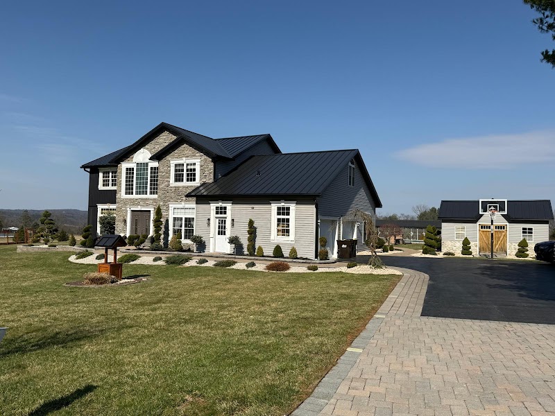 Finished residential exterior with dark roof, siding, stone, and clean driveway.